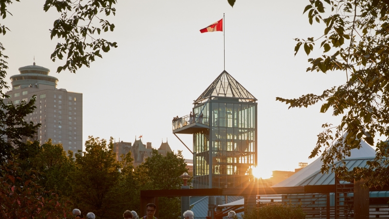A group of people peering over the tower balcony during sunset.