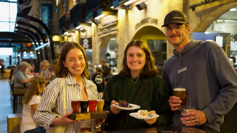 A group of friends holding beers from The Common.