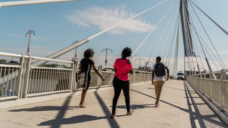 A group of friends walking over the Esplanade Riel.